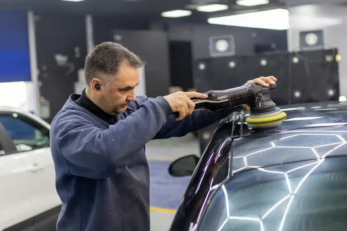 טכנאי RestorFX מבצע תיקון PDR מדויק בעזרת כלים ייעודיים על מכסה מנוע רכב